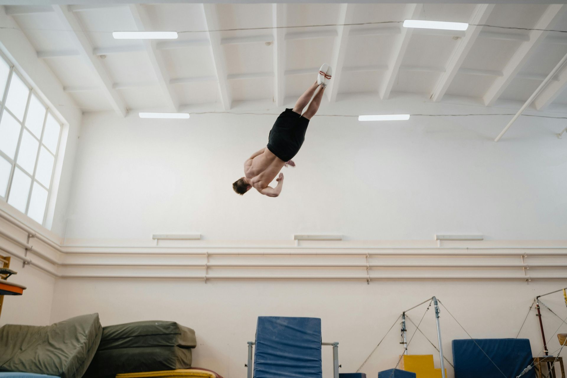 A gymnast is sitting on a balance beam covered in chalk.