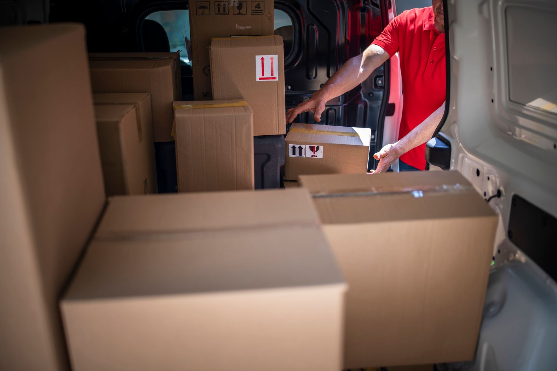 Un fattorino sta caricando delle scatole nel retro di un furgone.