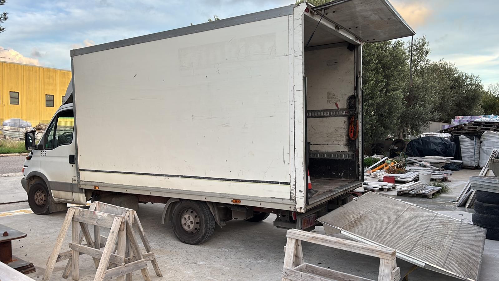 Un camion bianco è parcheggiato in un parcheggio con la portiera aperta.