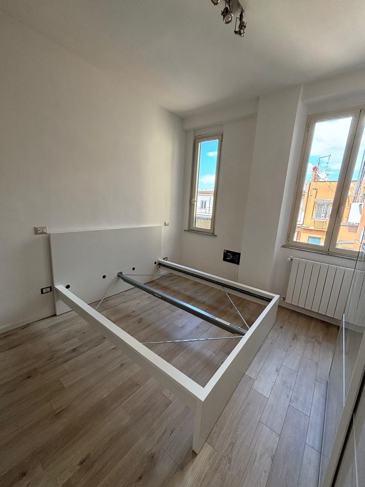 Una struttura del letto è posizionata in una camera da letto, accanto a una finestra.