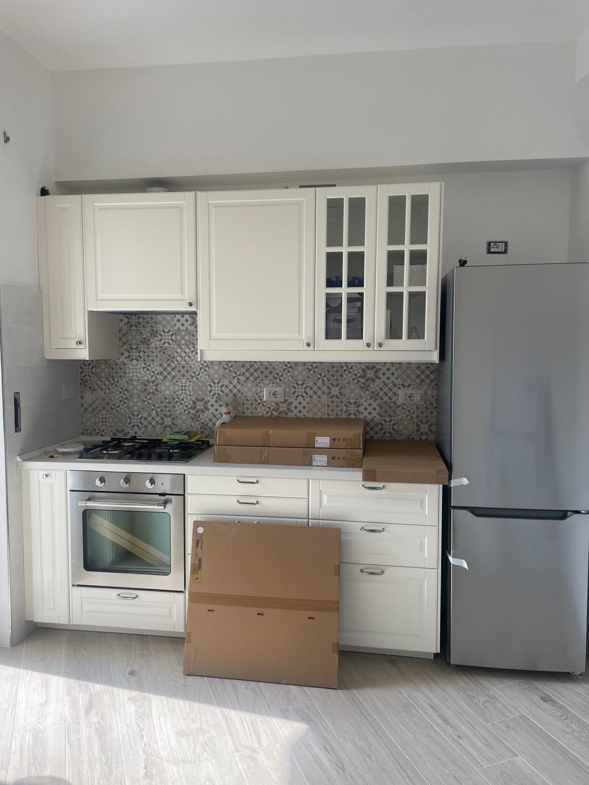 Una cucina con mobili bianchi e un frigorifero in acciaio inossidabile