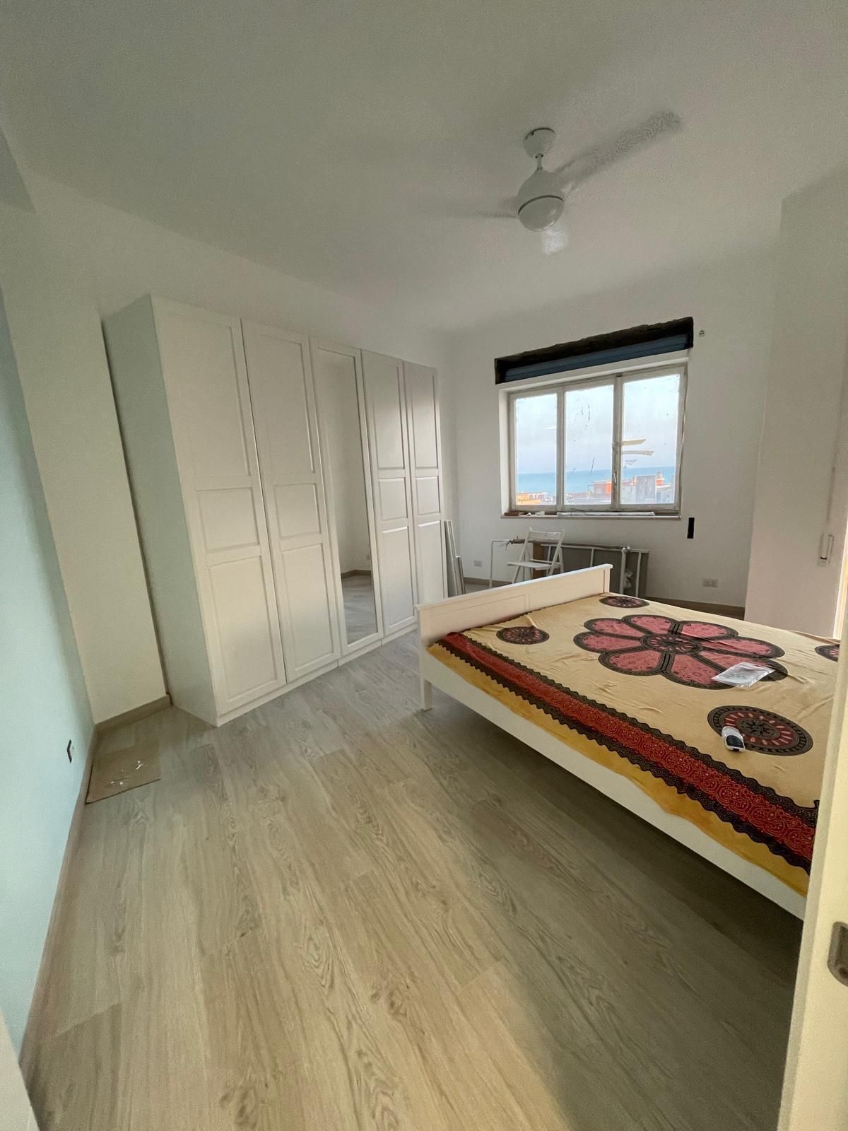 Una camera da letto con un letto, un ventilatore a soffitto e una finestra.