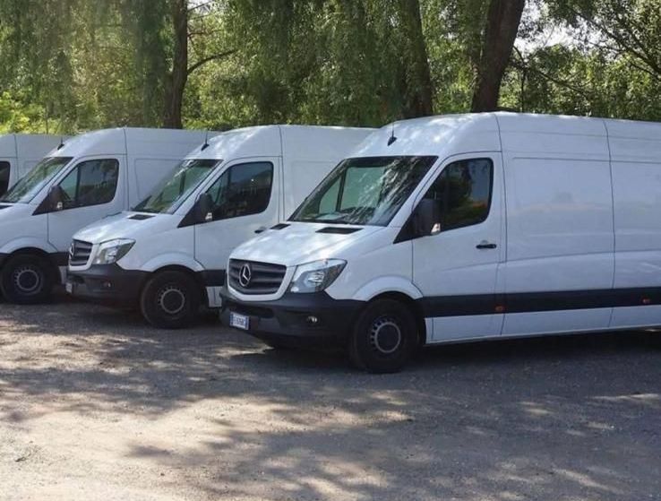 Una fila di furgoni bianchi sono parcheggiati in un parcheggio.