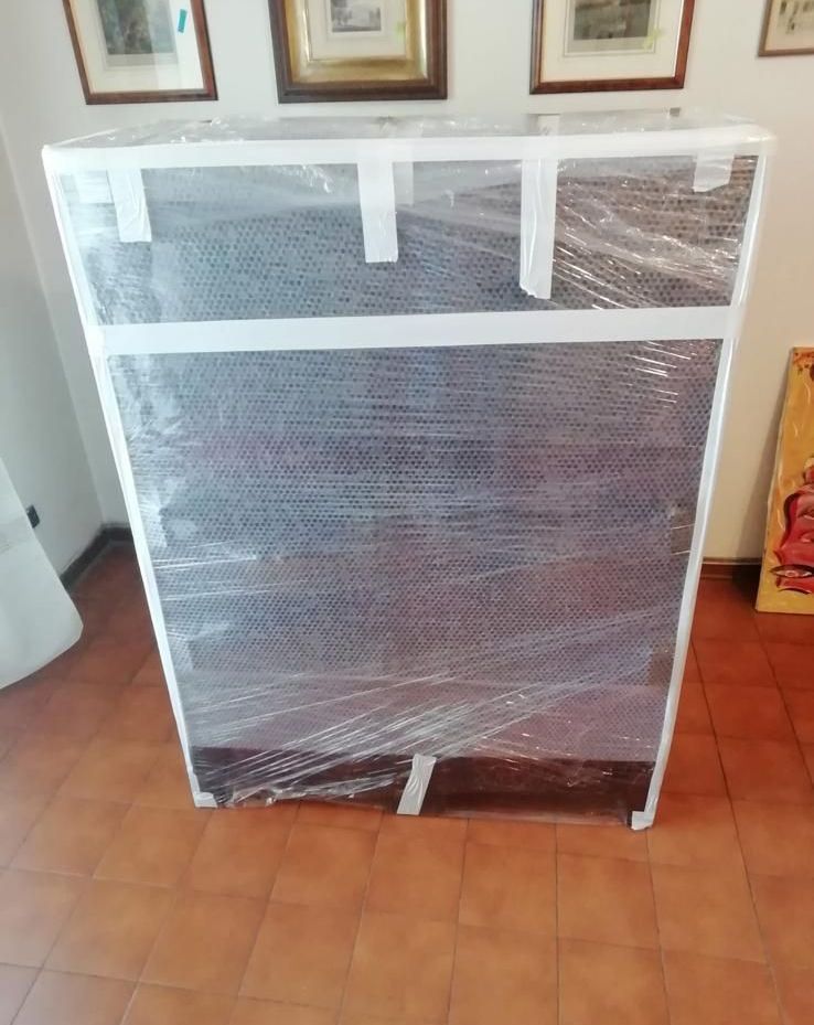 Un mobile avvolto nella plastica è appoggiato su un pavimento piastrellato.