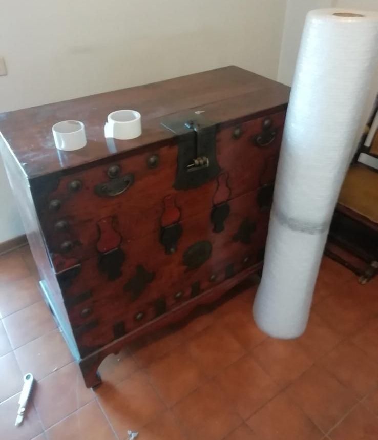 Una cassa di legno è appoggiata accanto a un rotolo di pellicola trasparente