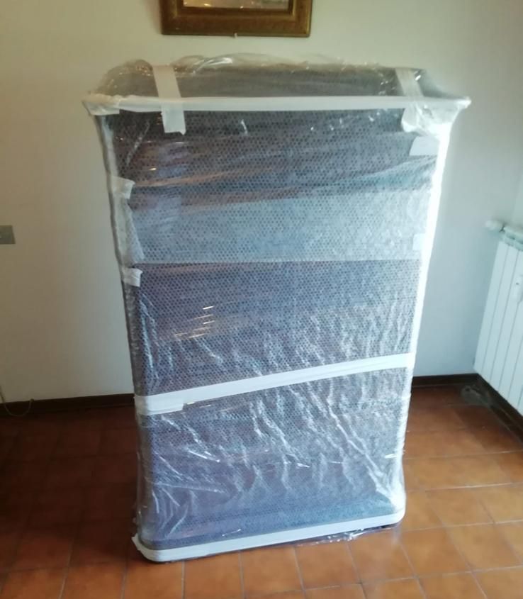 Una cassettiera è avvolta nella plastica in una stanza.