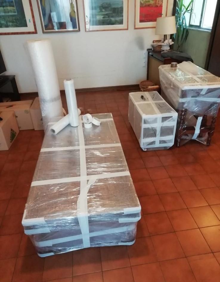 Un soggiorno pieno di scatole e un tavolo avvolto nella plastica.