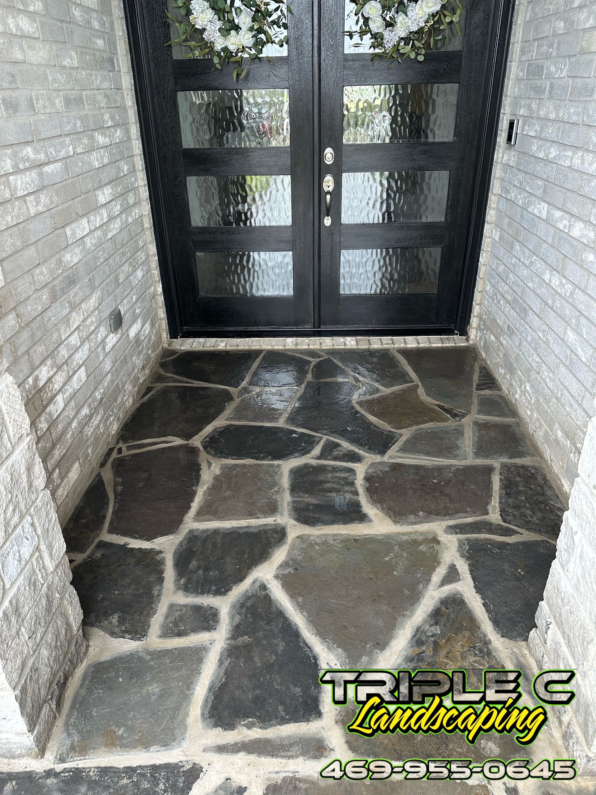 A stone walkway leading to a door with a wreath on it.