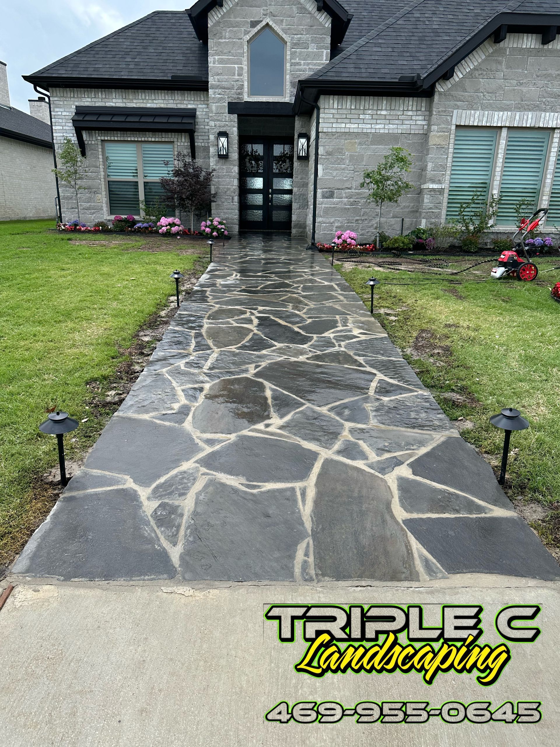 A stone walkway leading to a large brick house.