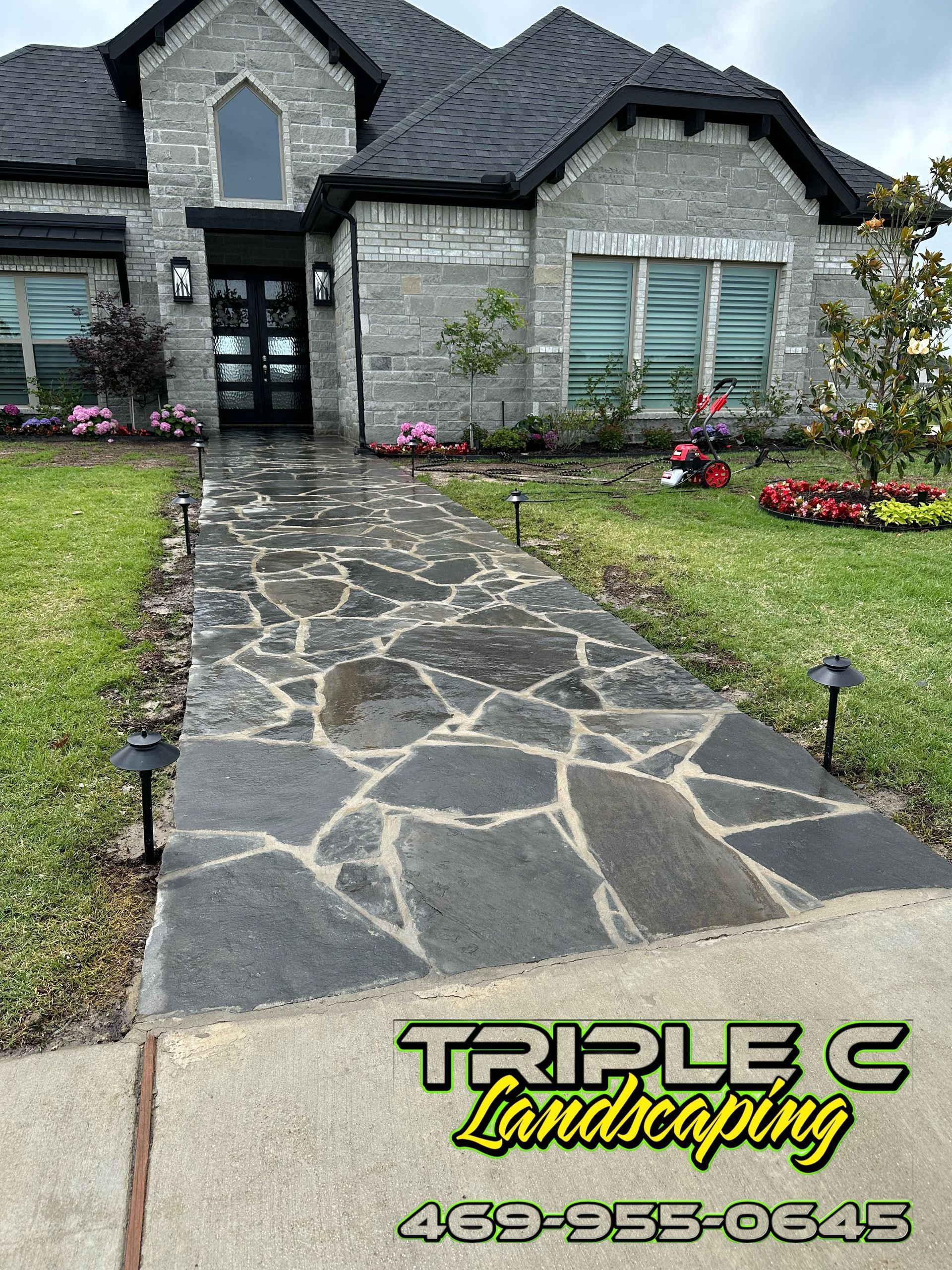 A stone walkway leading to a large brick house.