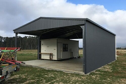 A Shed With A Trailer Parked Underneath It In A Field — Dunnrite Mareeba Sheds & Garages In Mareeba, QLD
