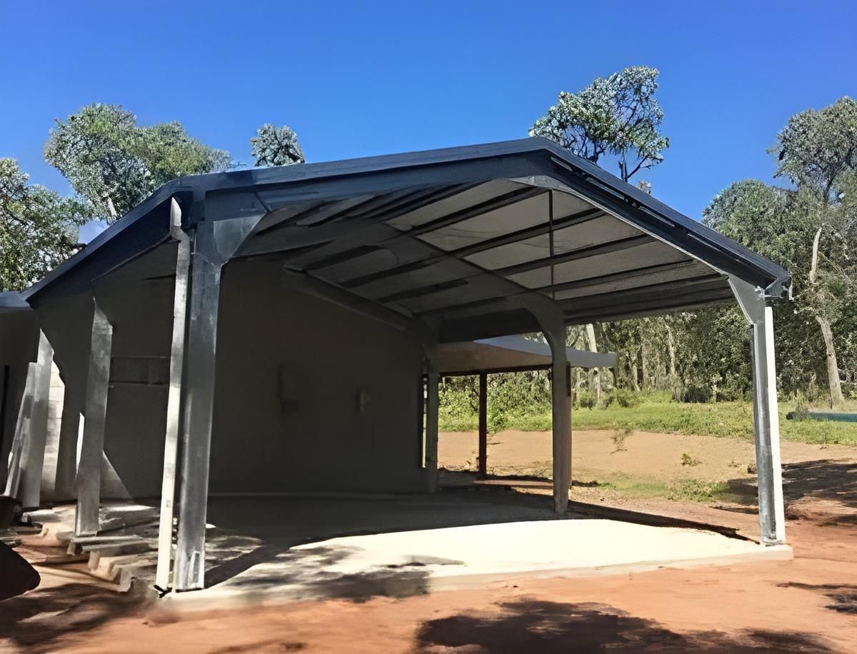 A Large Metal Structure With A Roof Is Sitting On Top Of A Dirt Field — Dunnrite Mareeba Sheds & Garages In Weipa, QLD