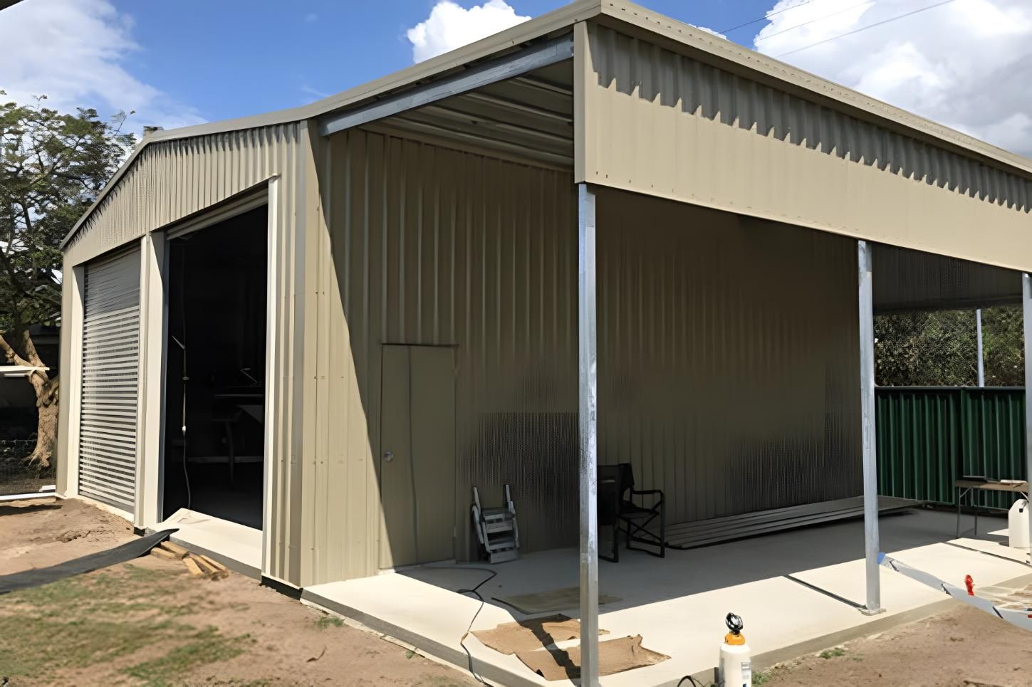 A Large Metal Building With A Covered Porch And A Large Garage Door — Dunnrite Mareeba Sheds & Garages In Mareeba, QLD