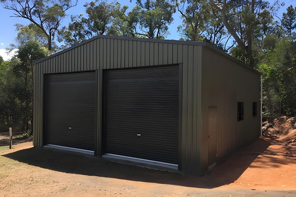 A Black Garage With Two Garage Doors Is Sitting In The Middle Of A Dirt Field — Dunnrite Mareeba Sheds & Garages In Mareeba, QLD