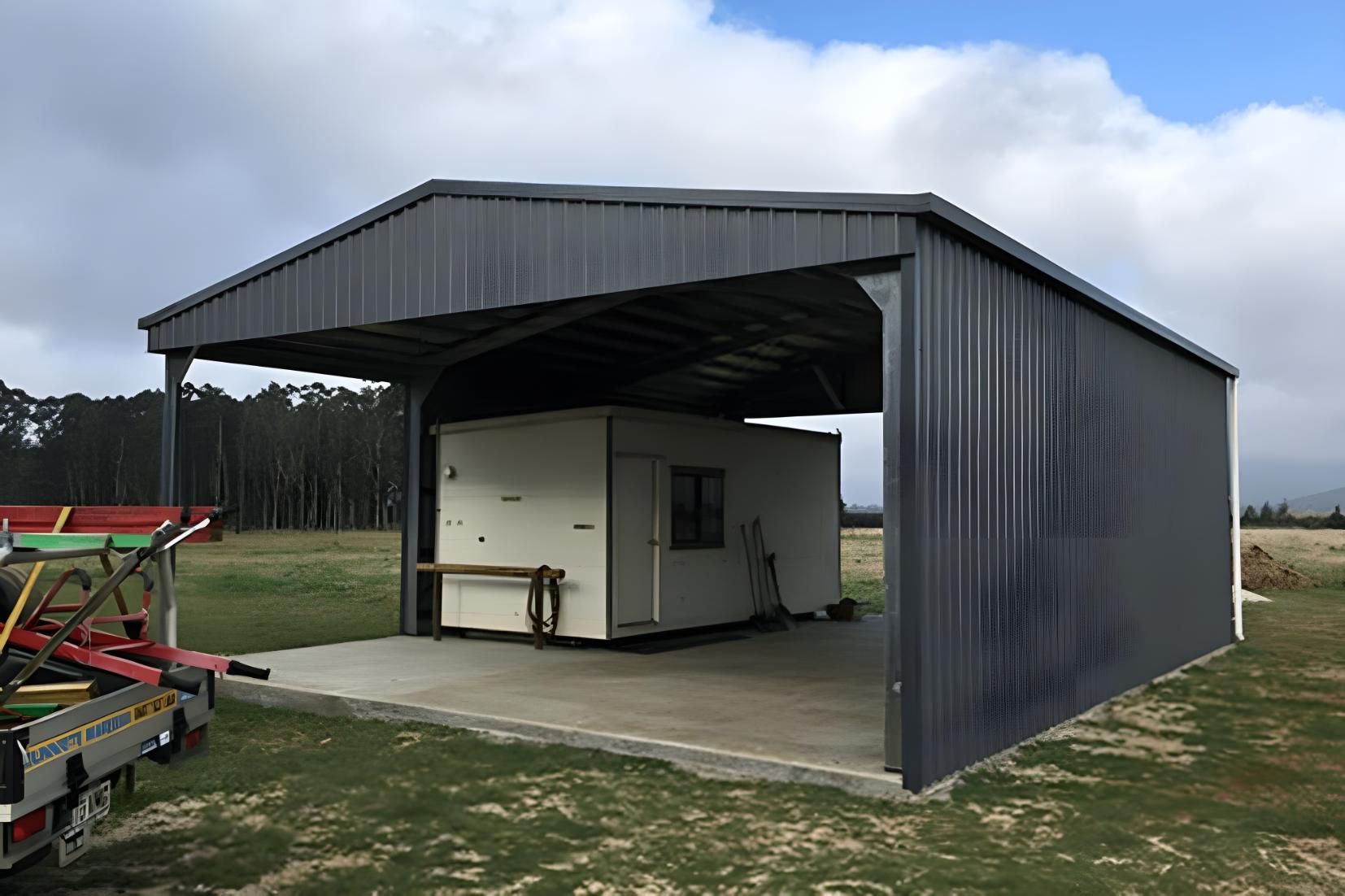 A Shed With A Trailer Parked Underneath It In A Field — Dunnrite Mareeba Sheds & Garages In Mareeba, QLD