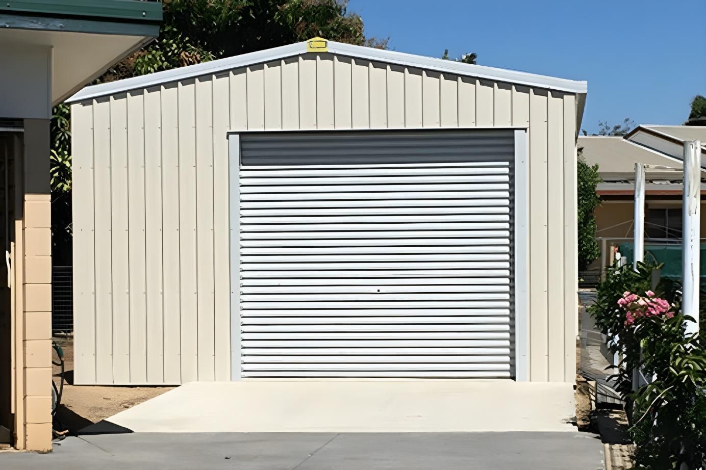A White Garage With A White Garage Door Is In Front Of A House — Dunnrite Mareeba Sheds & Garages In Mareeba, QLD