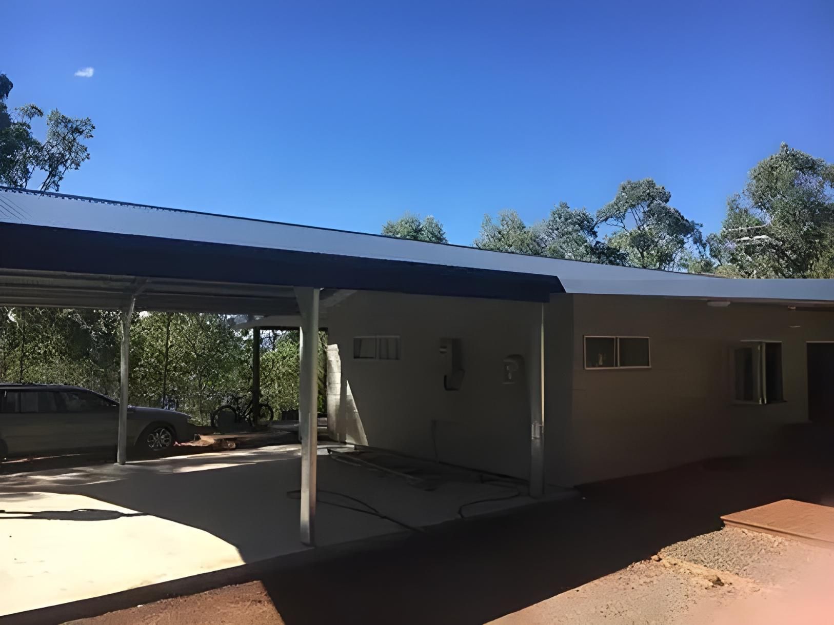 A Car Is Parked Under A Canopy In Front Of A House — Dunnrite Mareeba Sheds & Garages In Mareeba, QLD