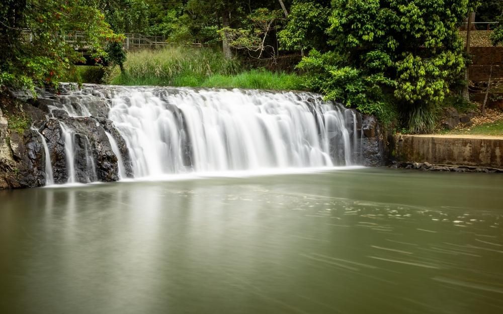 A Waterfall Is Surrounded By Trees And A Body Of Water — Dunnrite Mareeba Sheds & Garages In Malanda, QLD