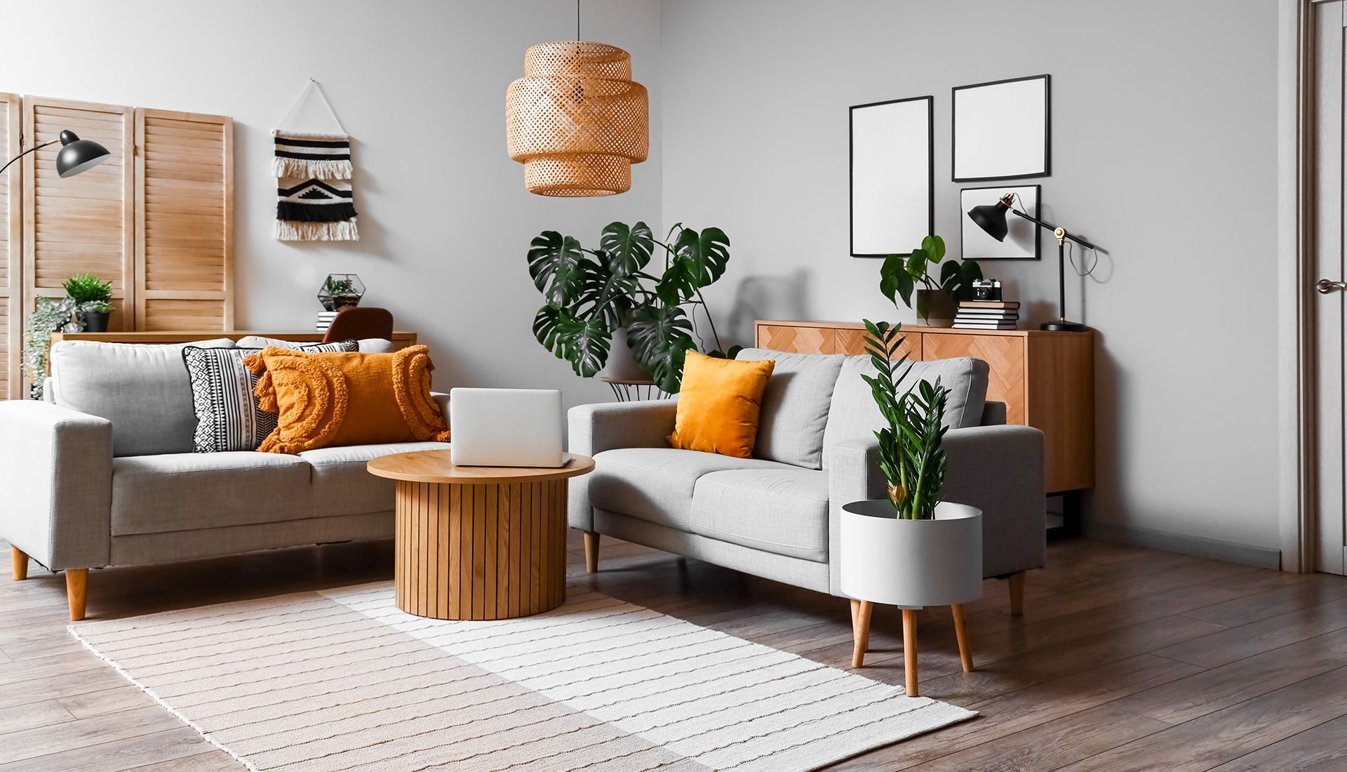 A modern living room with gray sofas, wooden furniture, plants, and decorative pillows.