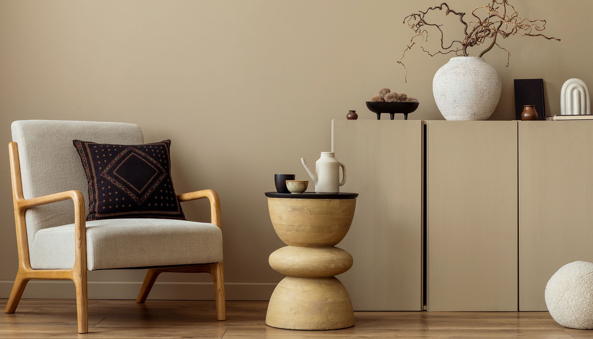 Cozy living room: beige chair with pillow, round side table with tea set, neutral color scheme.
