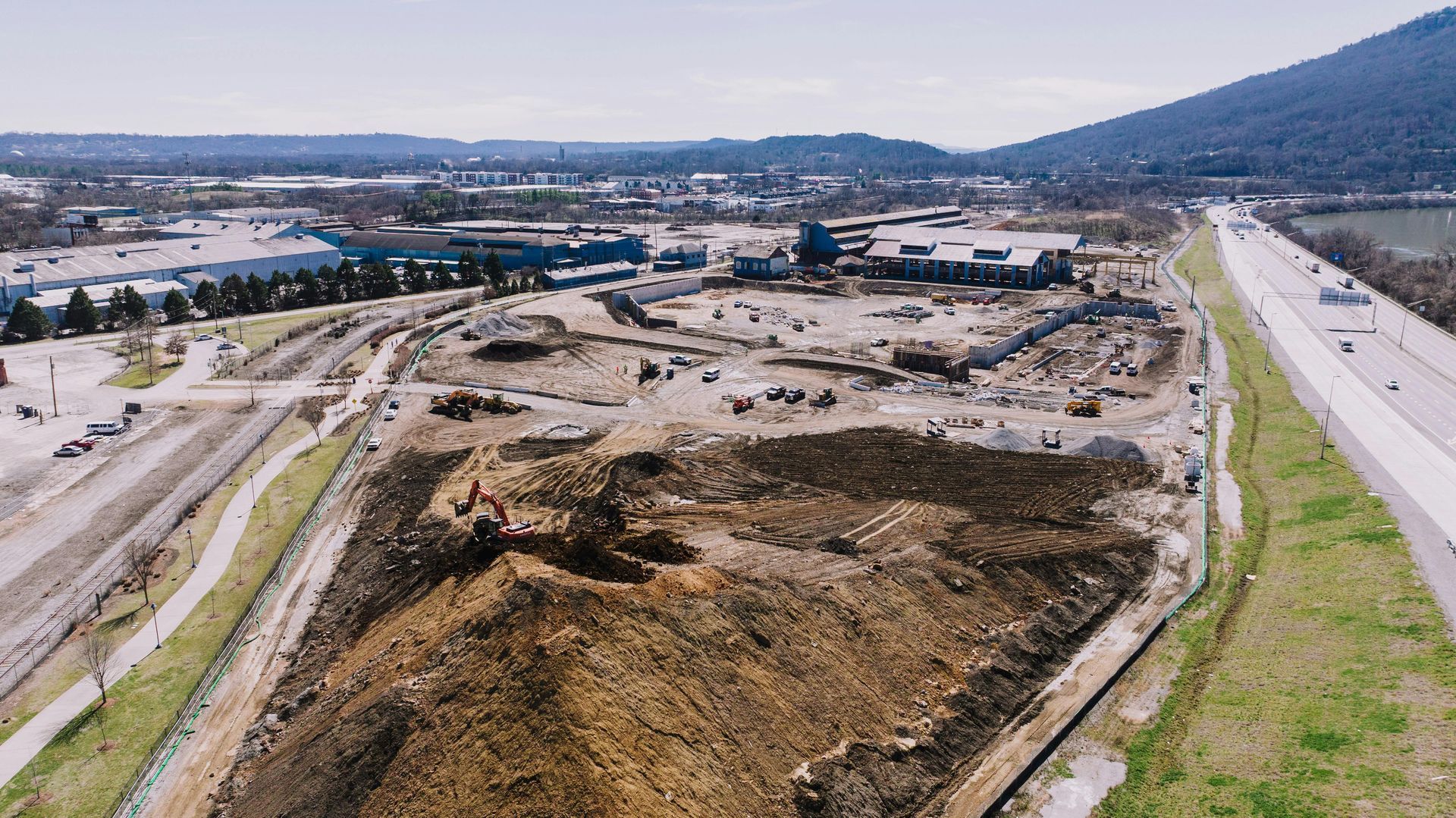 Large-scale land development project showing site preparation near highway and industrial district