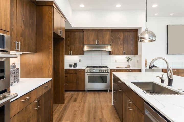 Modern kitchen with wood cabinets, white countertops, stainless steel appliances, and a central island.
