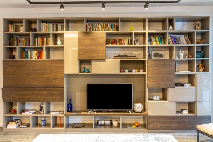 Modern wooden entertainment center with TV, bookshelves, and decorative items.