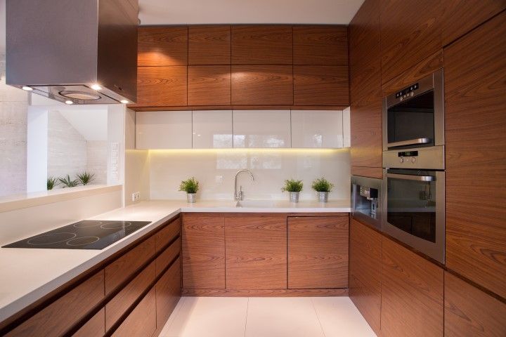 Modern kitchen with wood cabinets, white countertops, and stainless steel appliances.