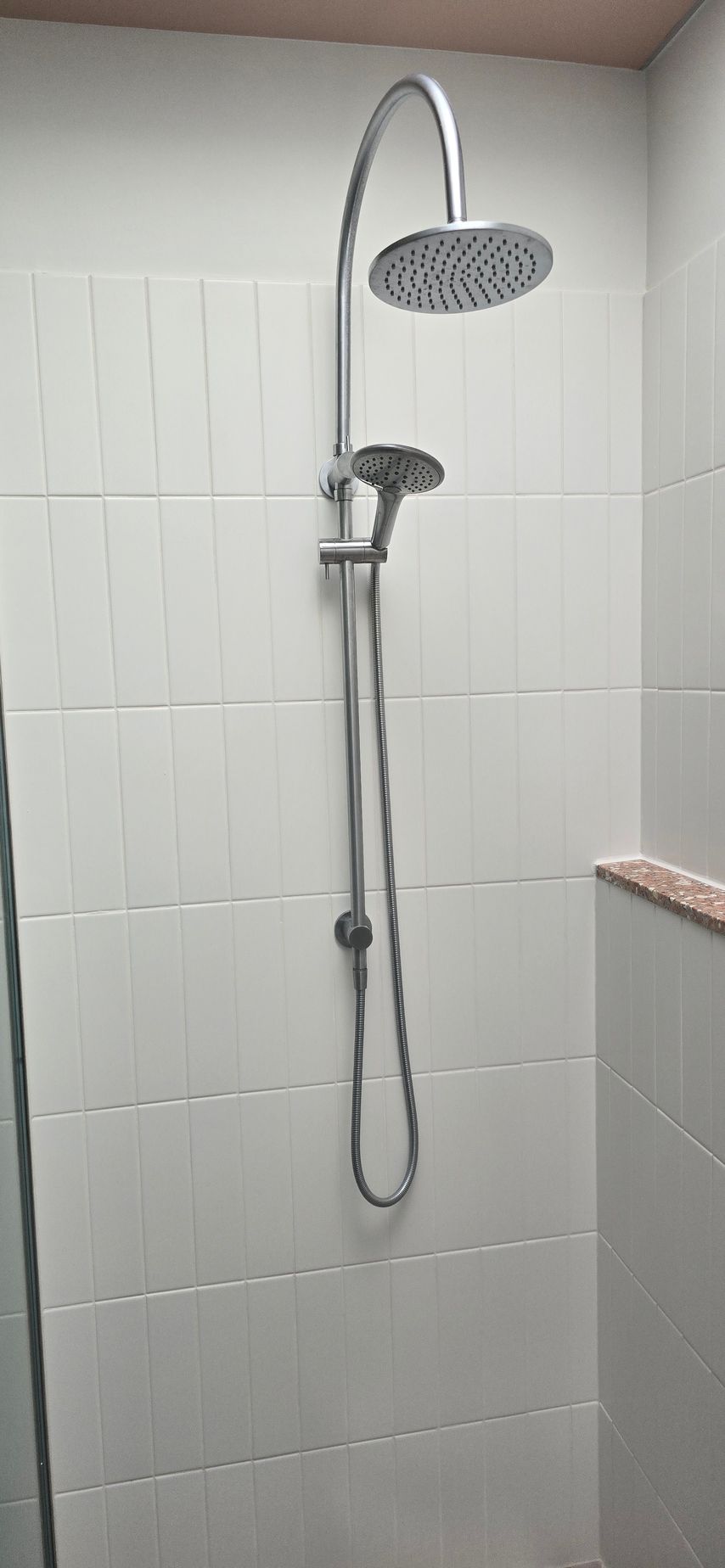 A shower head is hanging from the ceiling in a bathroom.