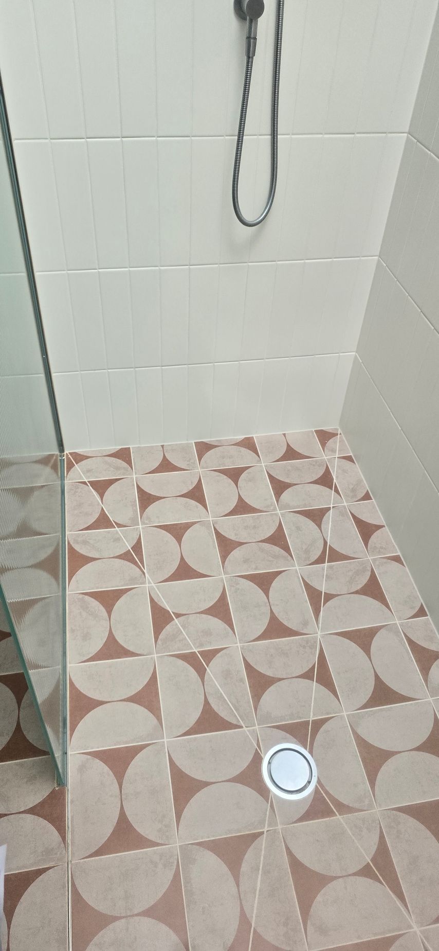 A shower with a tiled floor and a shower head.