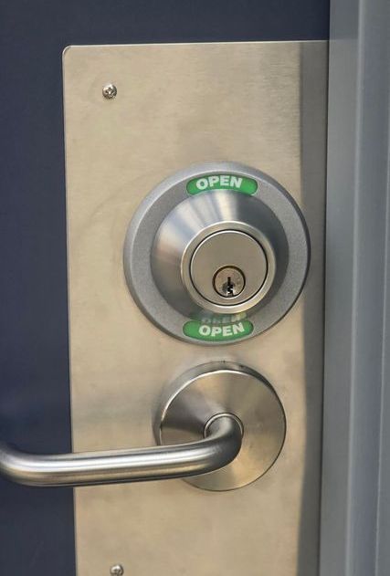 A close up of a stainless steel door lock on a blue door.