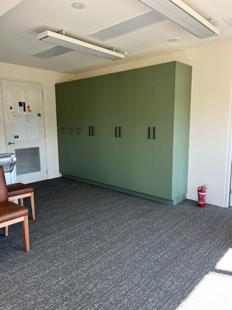 A room with green cabinets and a fire extinguisher on the floor