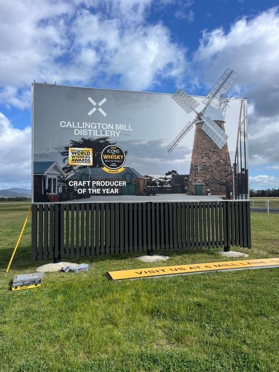 A large billboard with a windmill on it is sitting in the middle of a grassy field.
