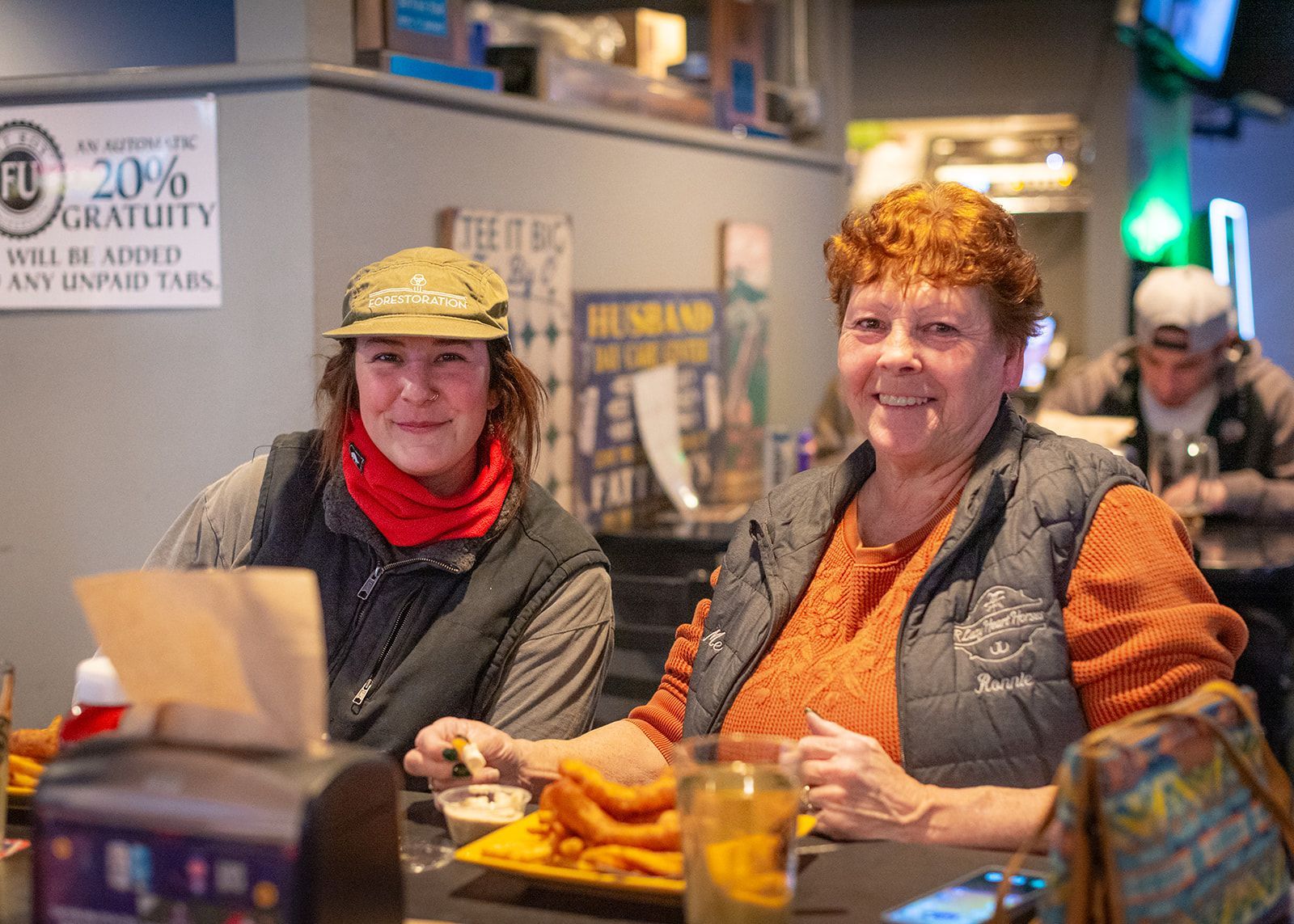 Two women are sitting at a table in a restaurant eating food.