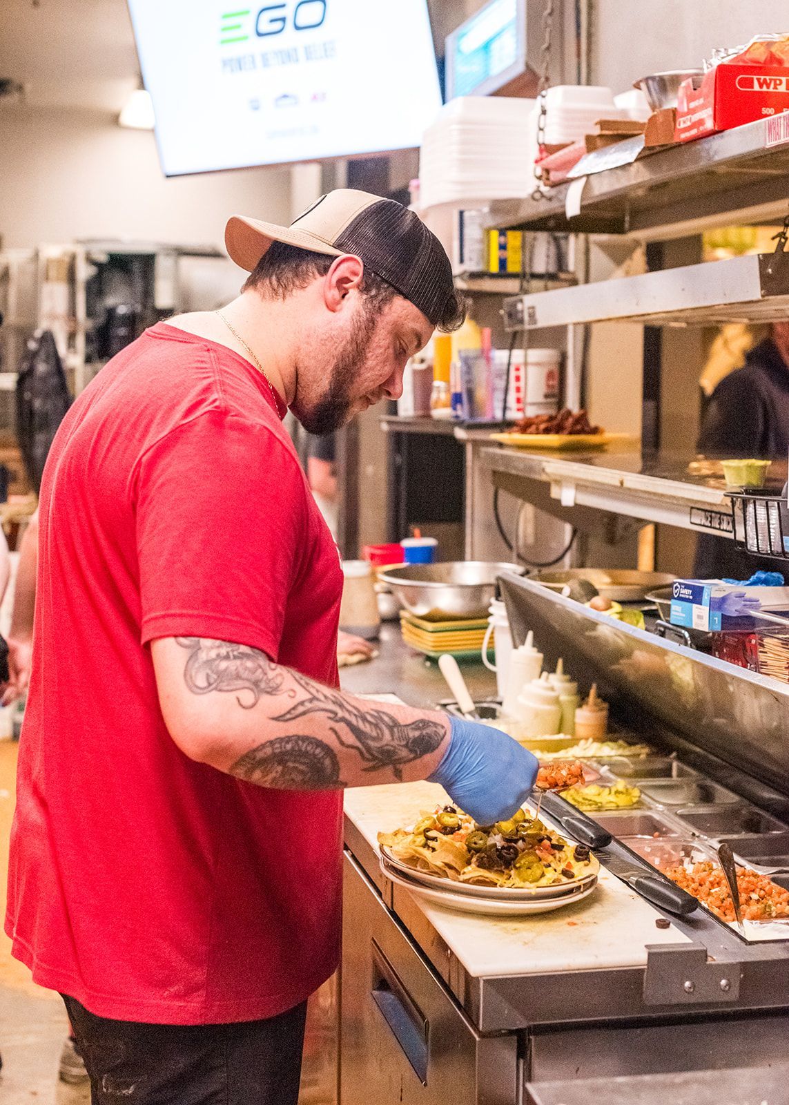 A man in a red shirt is preparing food in a kitchen.