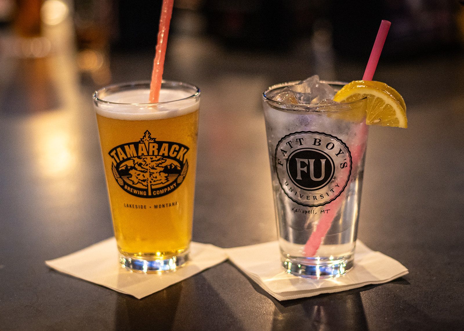 A glass of beer and a glass of water on a napkin on a table.