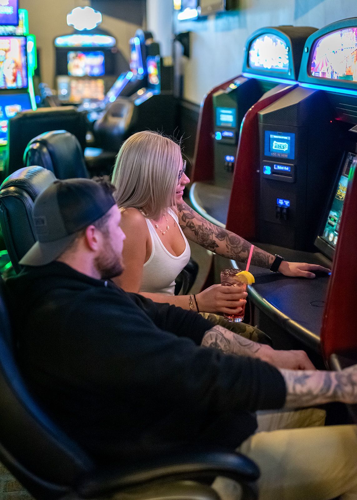 A man and a woman are playing slot machines in a casino.