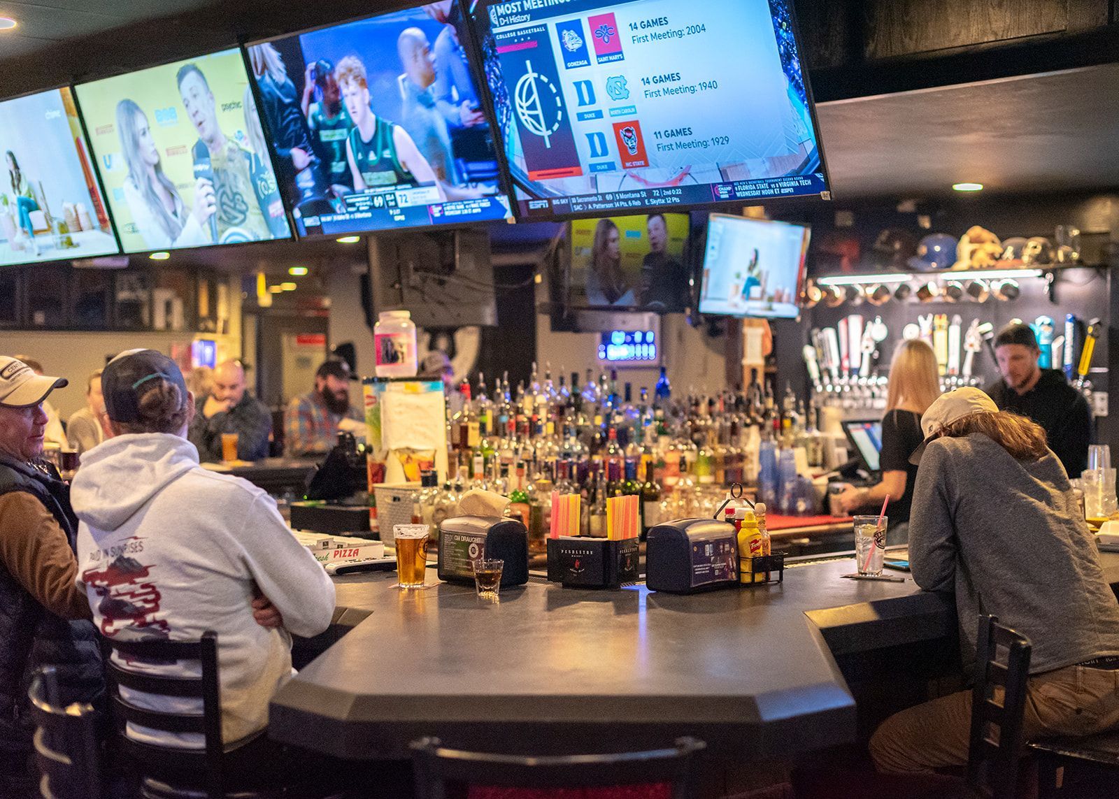 A group of people are sitting at a bar in a restaurant.