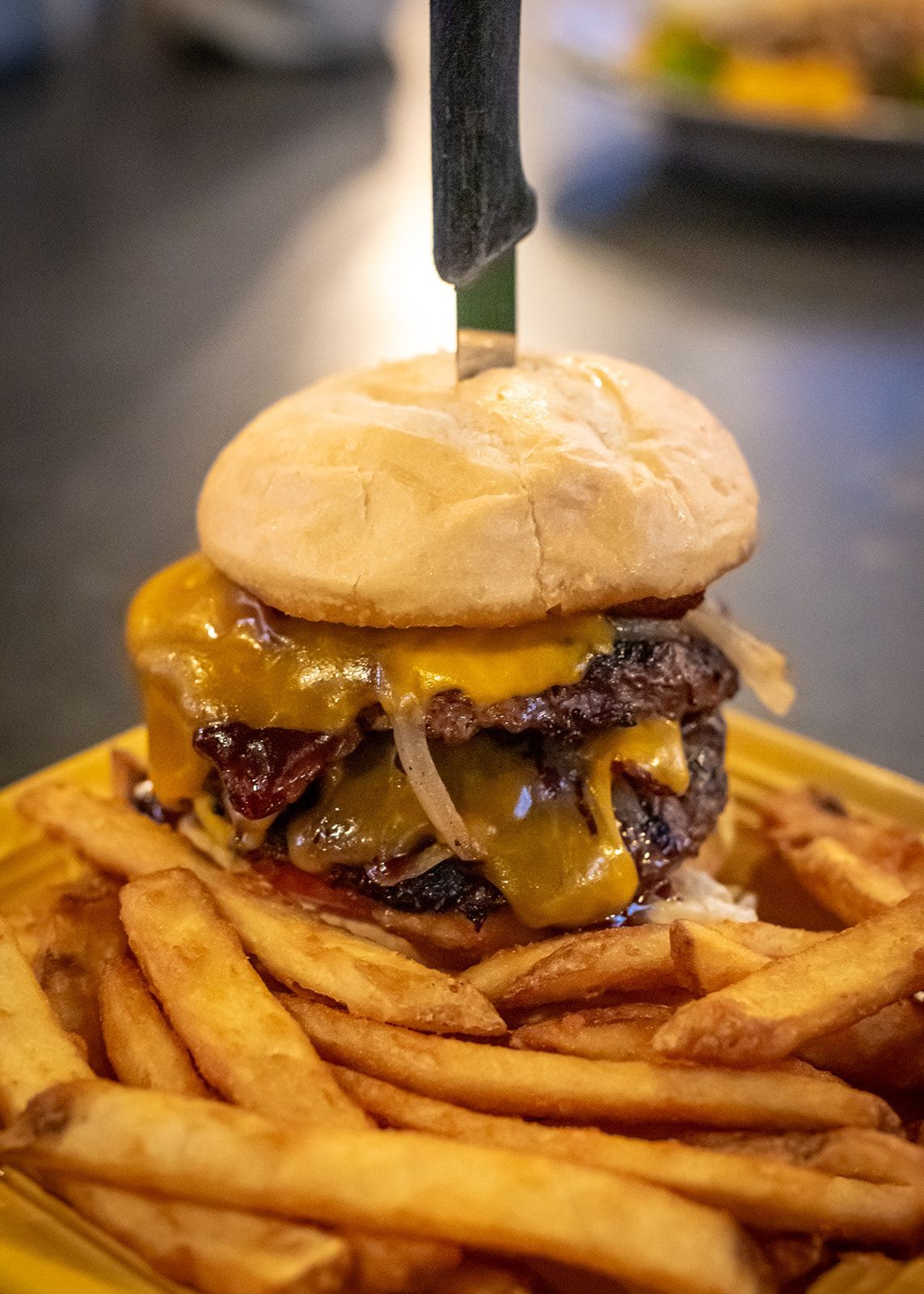 A hamburger and french fries on a yellow plate