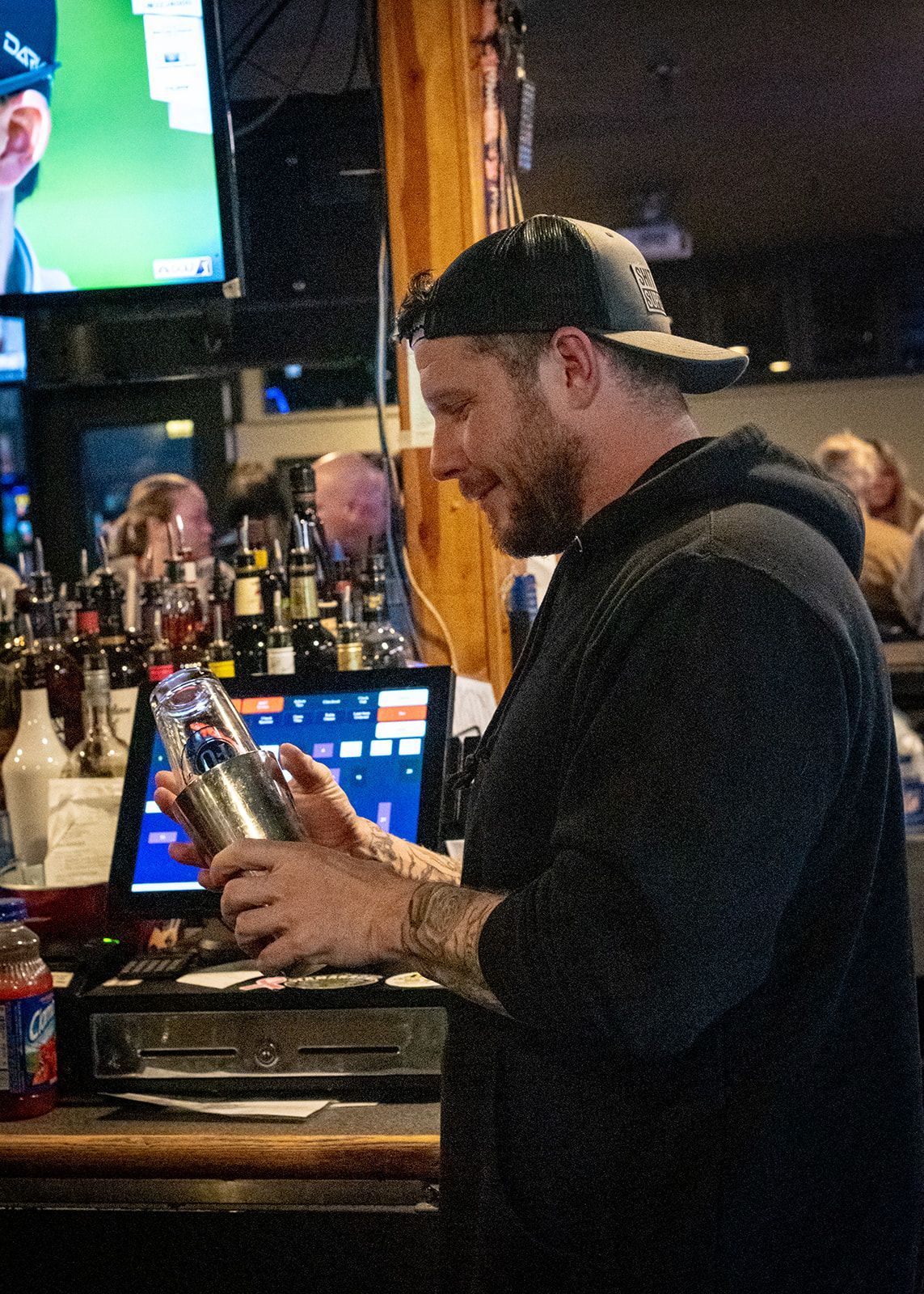 A man is shaking a drink in a bar.
