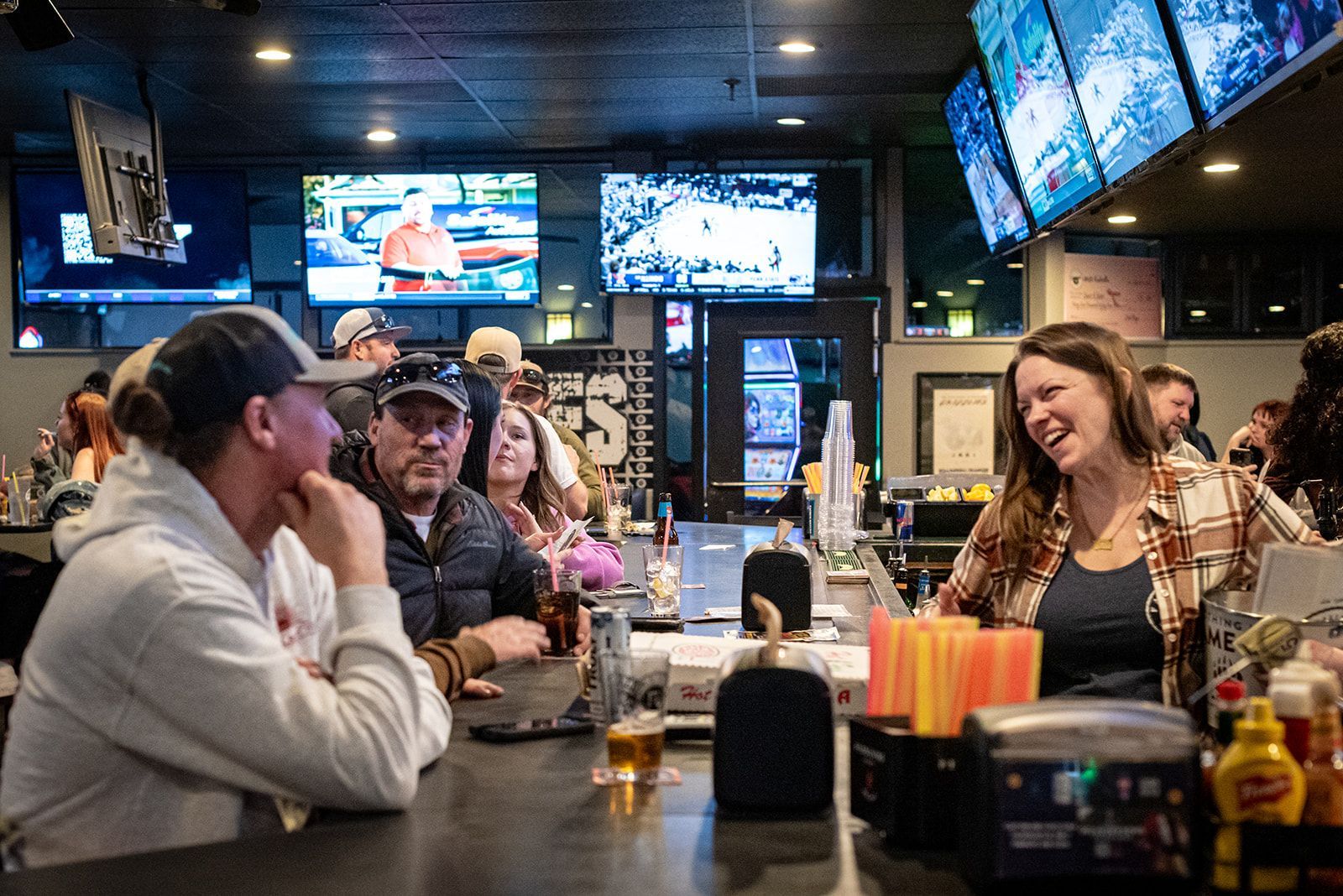 A group of people are sitting at a bar talking to each other.