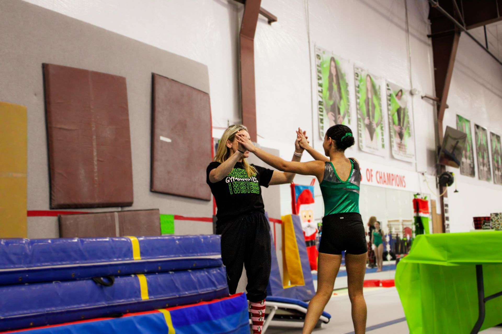 Gymnastics coach and athlete practicing a stunt on mats in a gymnasium