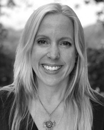 A black and white photo of a woman wearing a necklace and smiling.