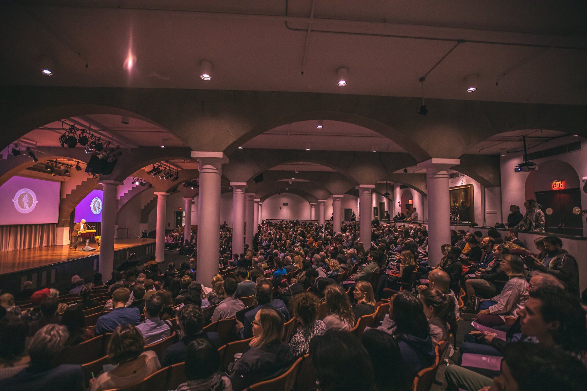 A large crowd of people are sitting in a large auditorium.