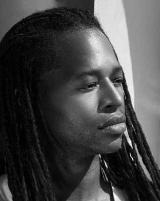 A black and white photo of a man with dreadlocks.