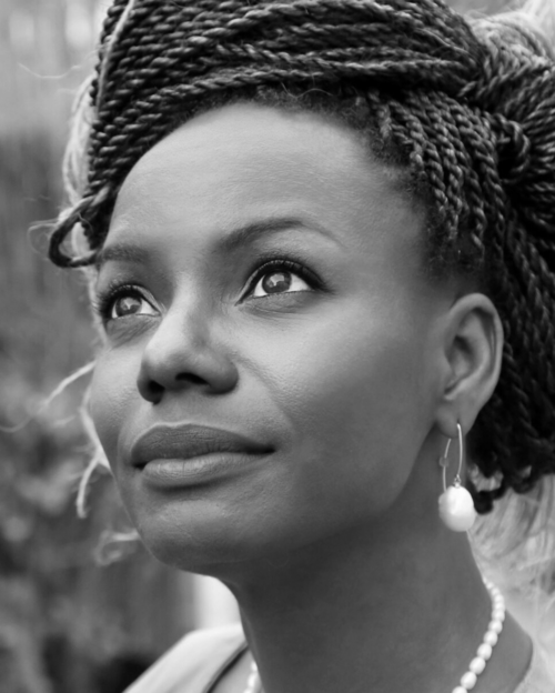 A black and white photo of a woman with braids and pearls