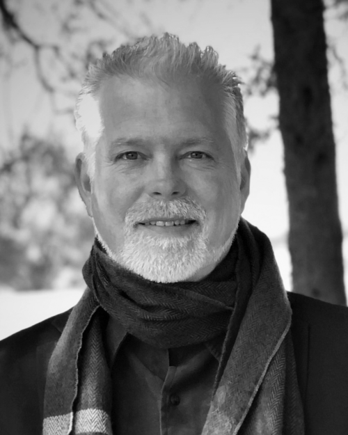 A black and white photo of a man with a beard wearing a scarf.