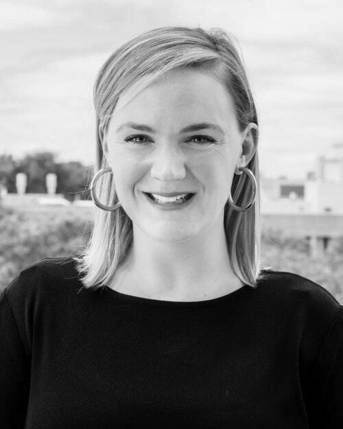 A woman wearing hoop earrings is smiling in a black and white photo.