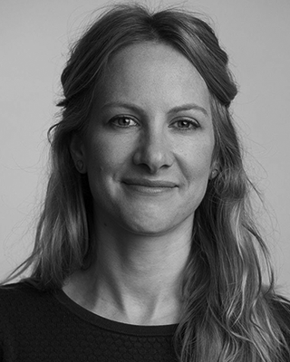A woman with long hair is smiling in a black and white photo.