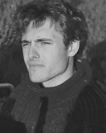 A black and white photo of a man wearing a scarf and a sweater.